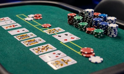 Blackjack Tisch mit Karten und Chips auf gr&uuml;nem Filz im blau beleuchteten Casino